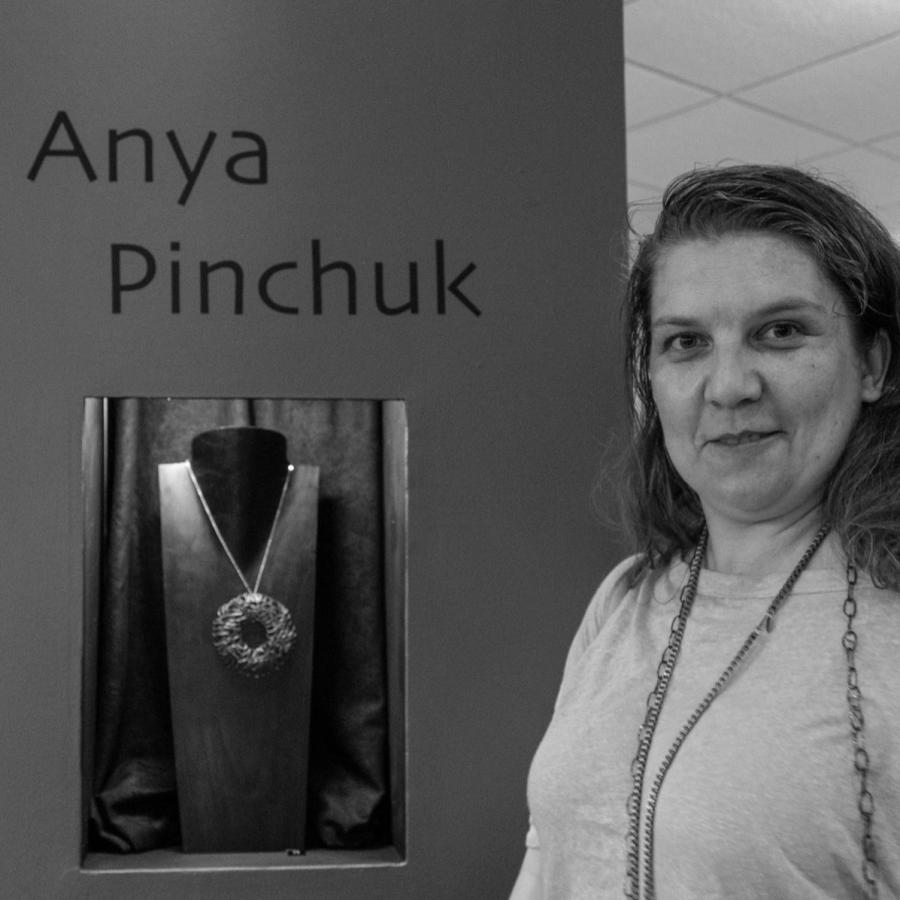 A woman standing next to a display with the name "Anya Pinchuk" on an orange wall.