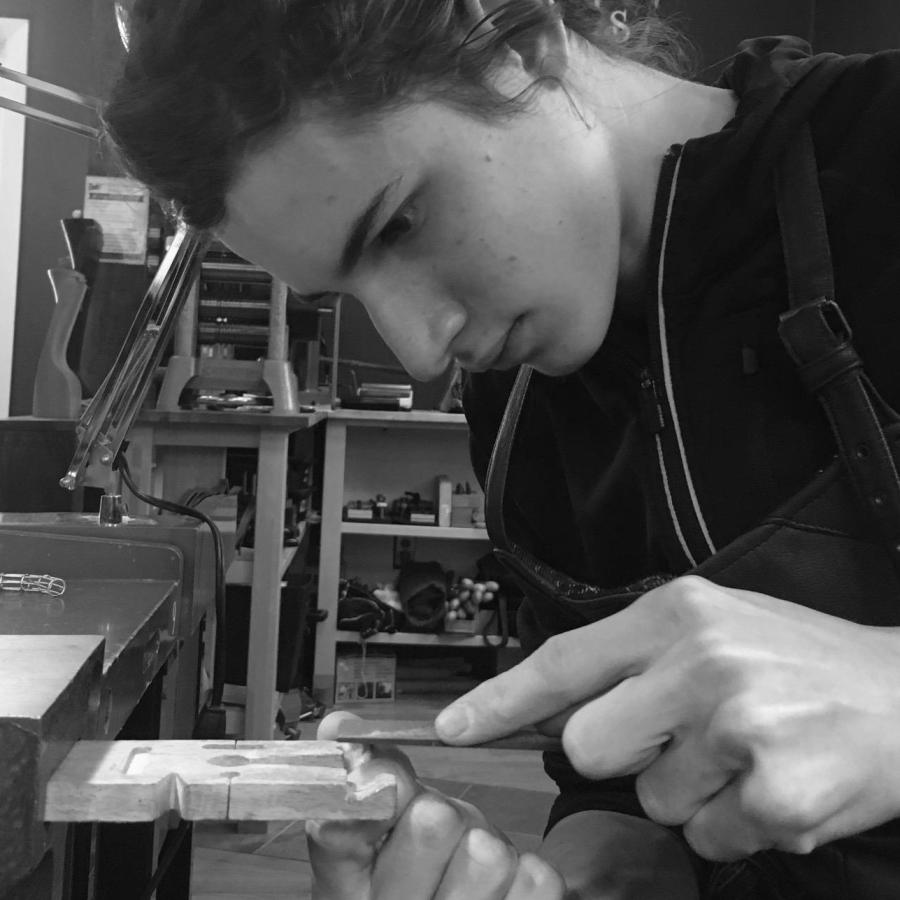 A young person filing metal at a workbench in a brightly lit workshop.