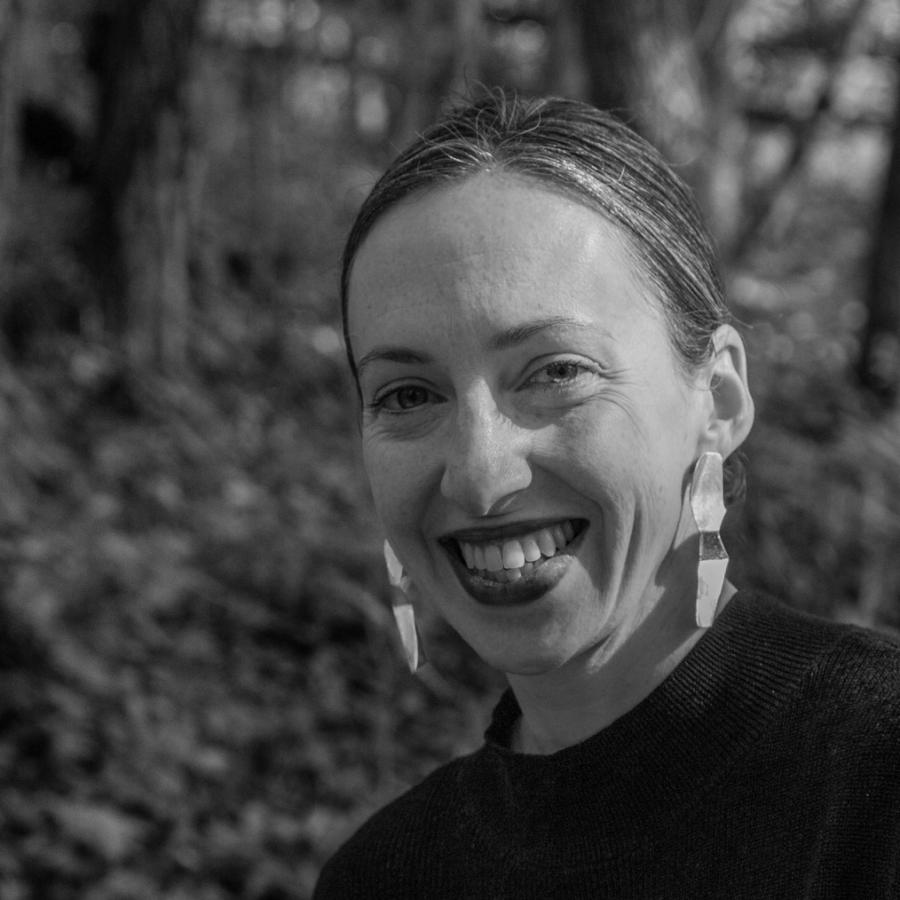 Photograph of a smiling woman in a lush green forest.