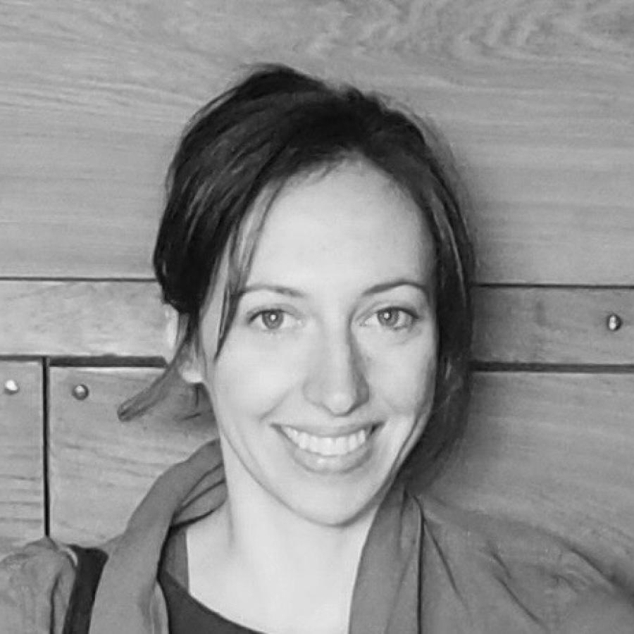 Black and white photograph of a smiling woman against a wood-paneled wall.