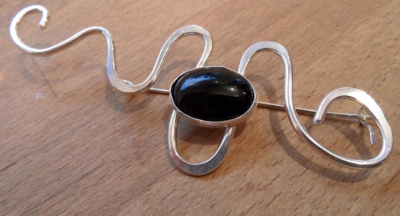 A silver pin with a black stone