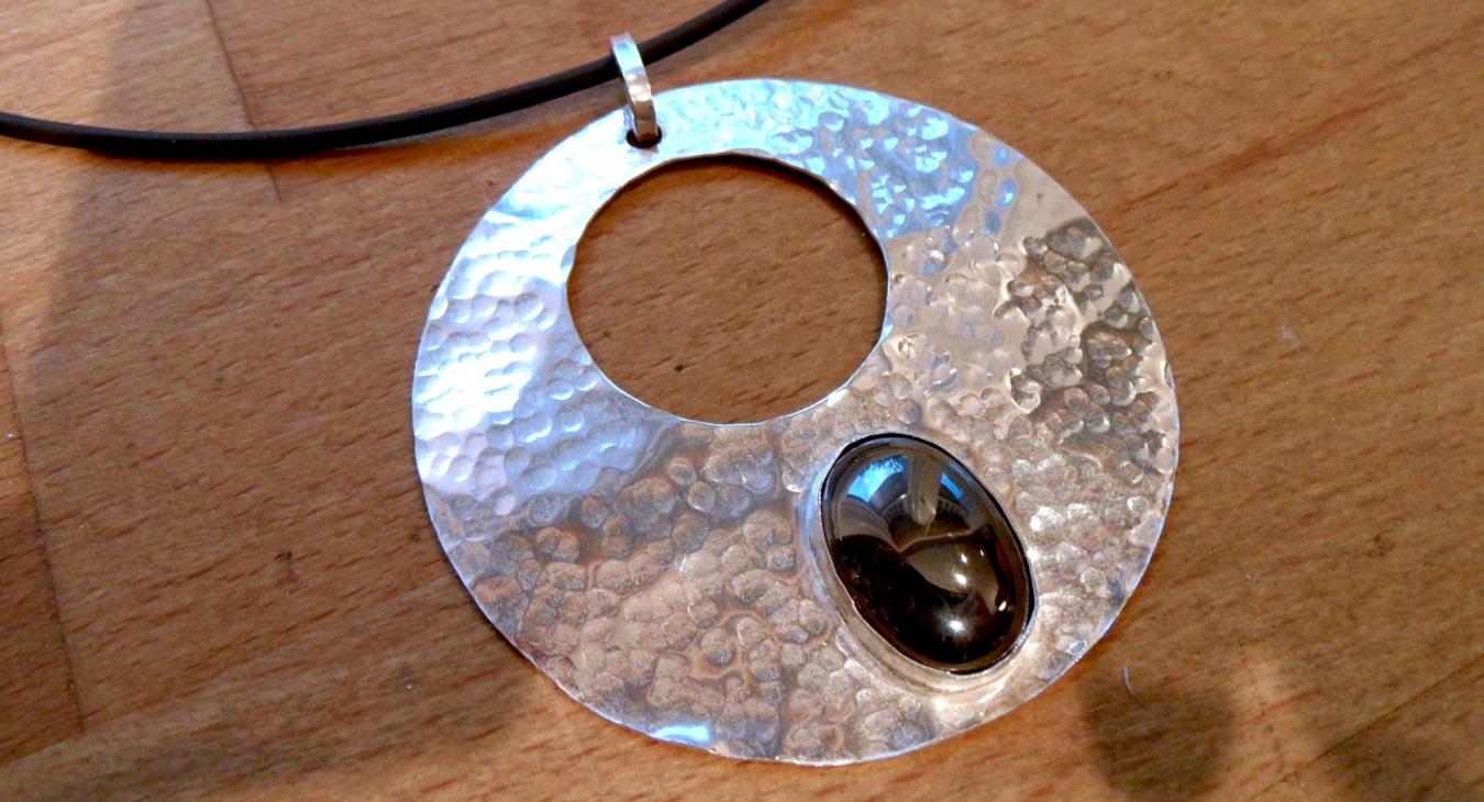 A silver pendant with a stone