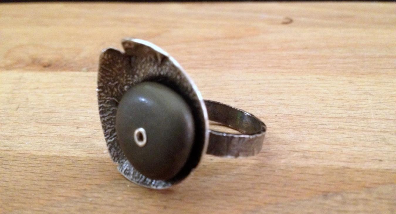 A silver ring with a drilled riveted stone