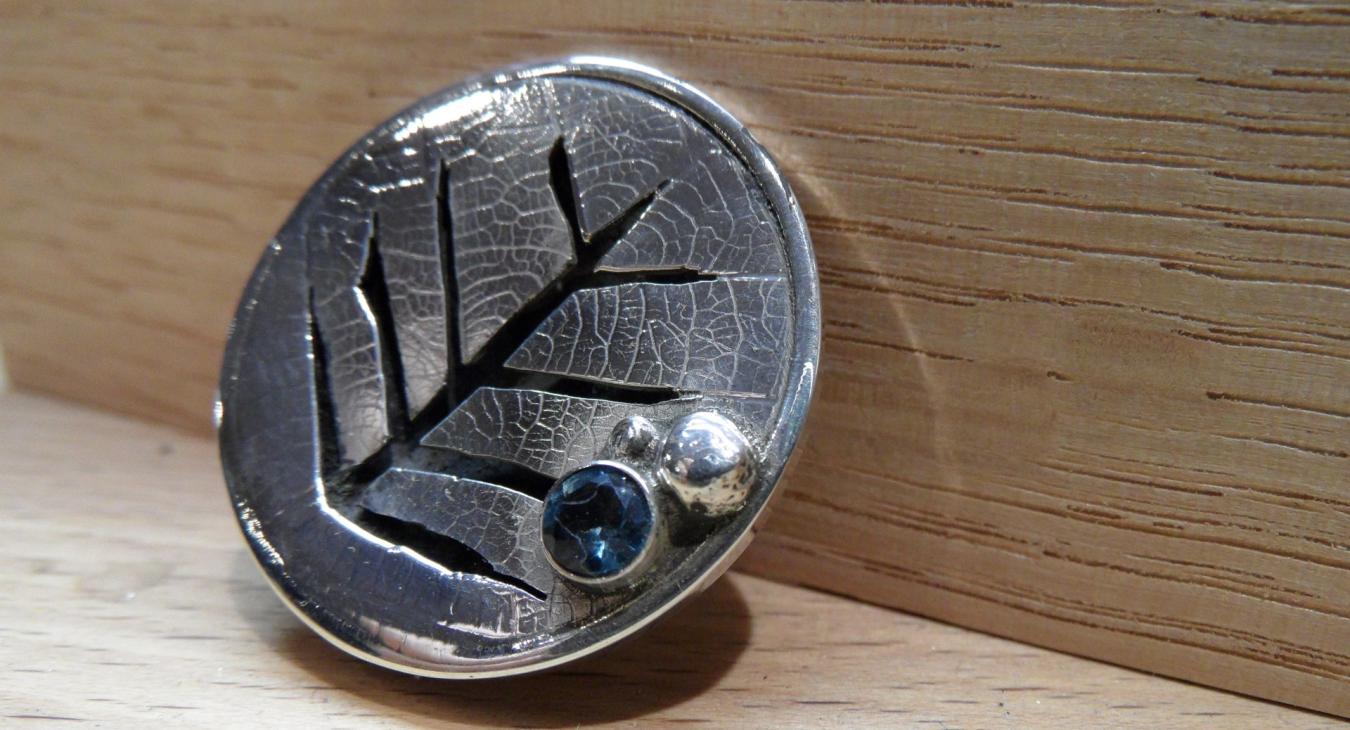 Layered broach with leaf pattern and blue gem stone 