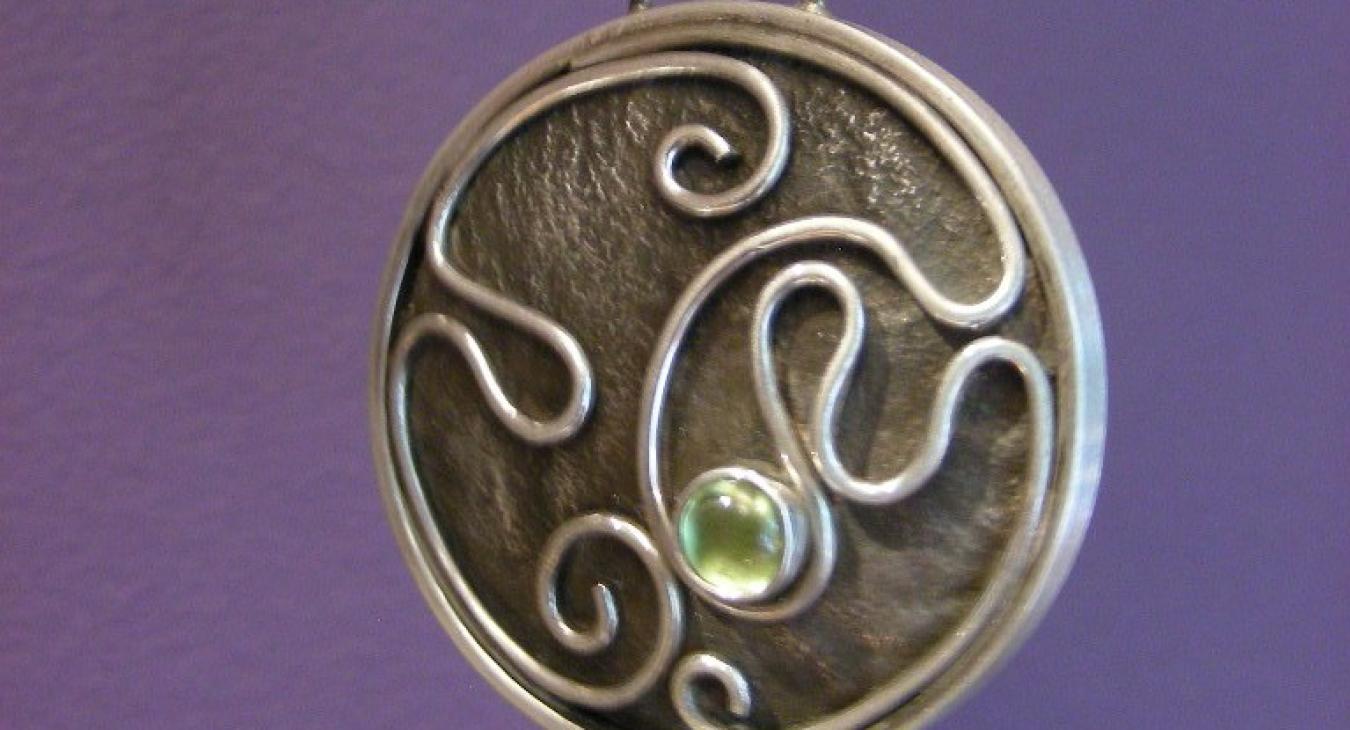 Oxidized circular silver pendant with wire and peridot design