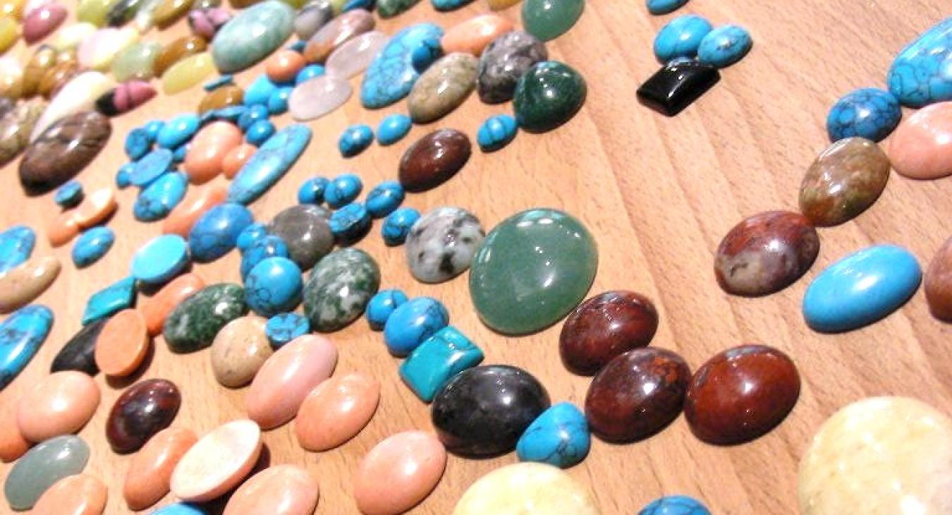 Cabochons in multiple colors laid out on the bench