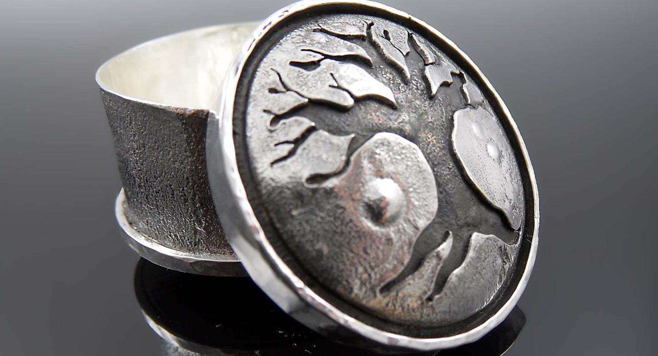 Silver three-footed box with an appliqué lid with a tree image
