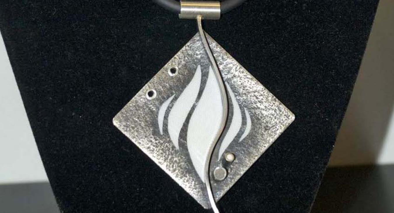 Textured diamond shaped silver pendant with white flames