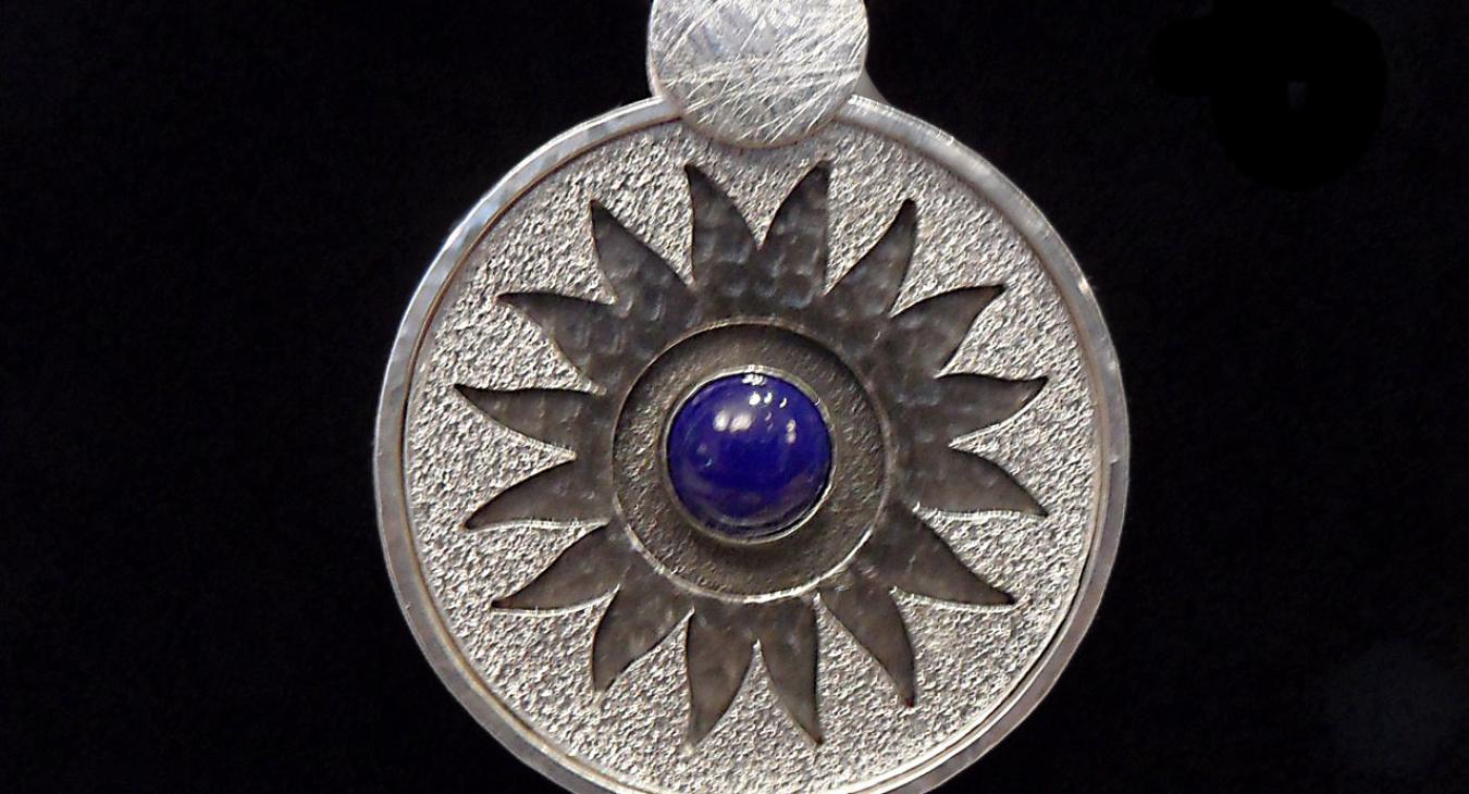 Circular layered pendant with oxidized sunflower design and lapis