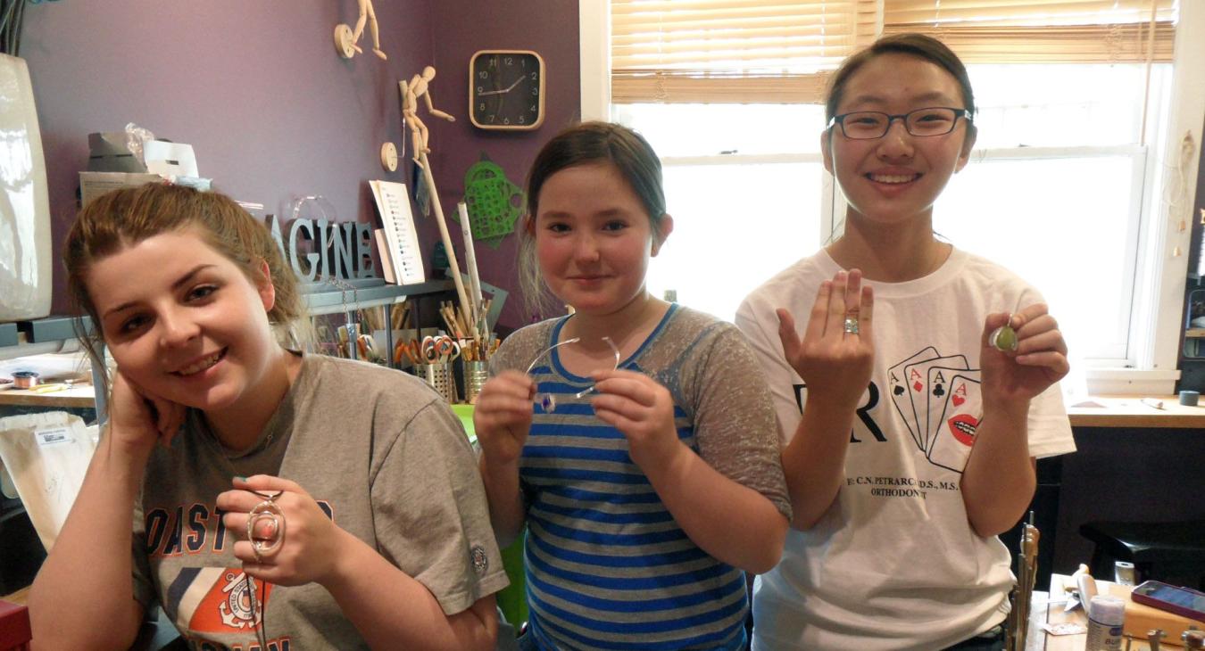 three students holding their projects in the studio