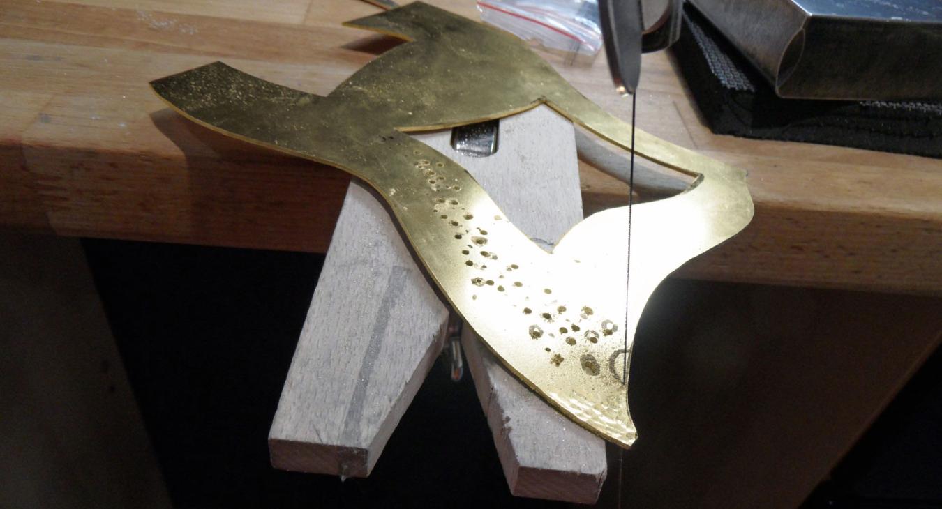 sawing and piercing the brass piece on bench pin