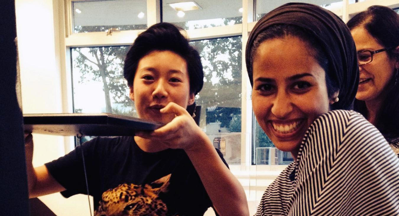 Kelly, Ilsa and Mawadda smiling at camera while assembling display stands