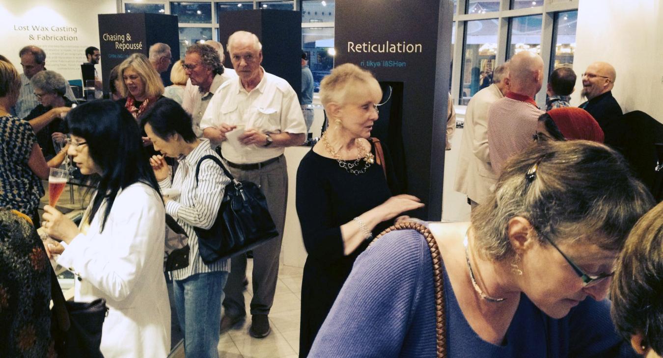People gathered in gallery with refreshments and looking at the work