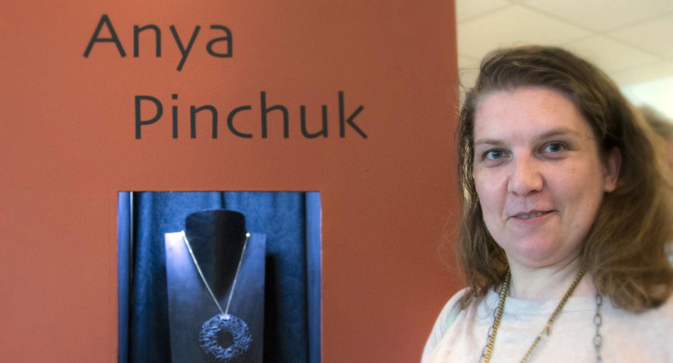 Anya standing by a tower display with her name and work