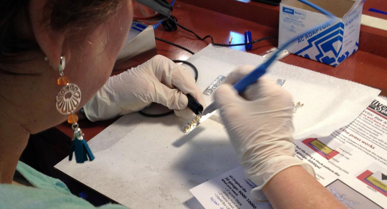 Shelly using the plating pen on rectangular silver pieces 