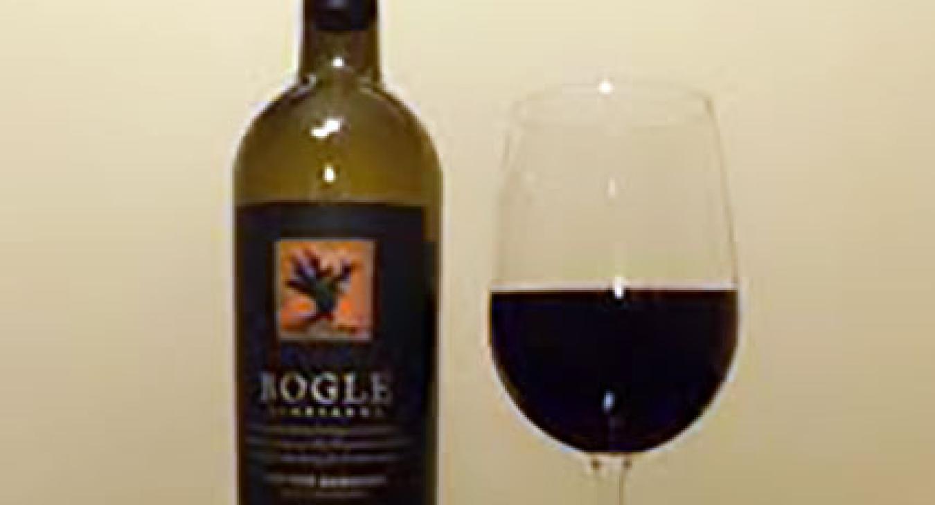 Bottle of red wine, uncorked next to filled wine glass