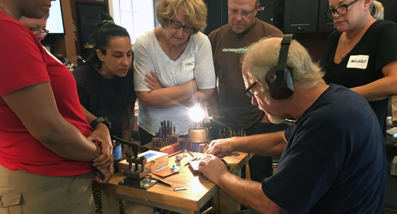 alan showing stamping with students gathered around bench