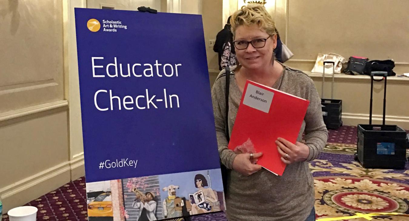 Blair standing next to educator event sign