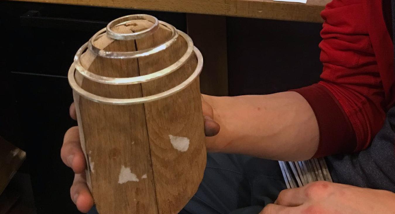Louis holding wooden jig to form wire cage
