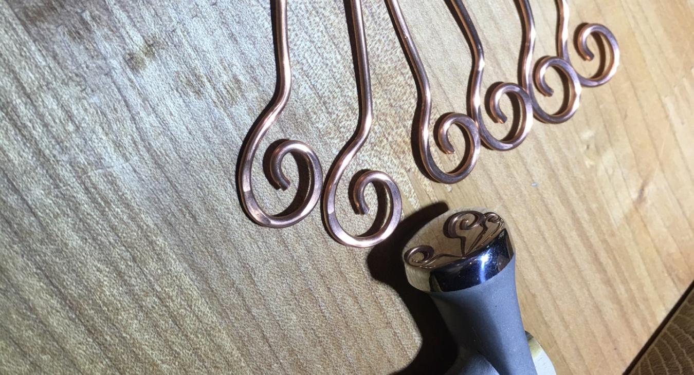 copper stakes on bench next to hammer