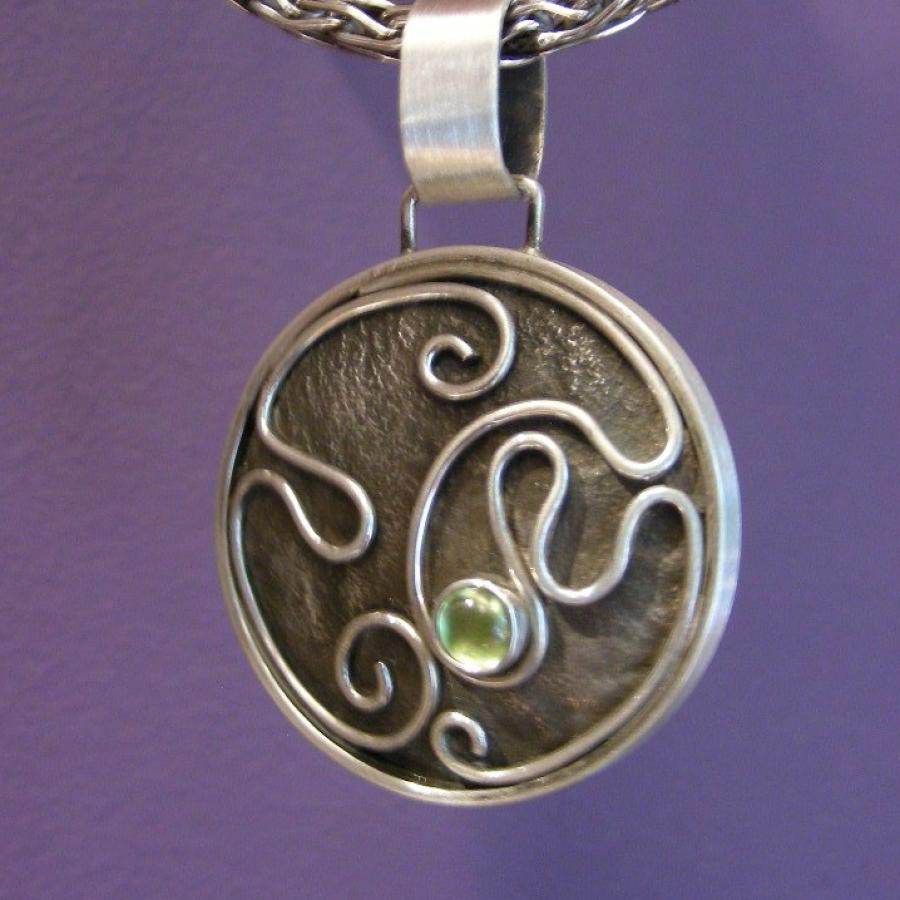 Oxidized circular silver pendant with wire and peridot design