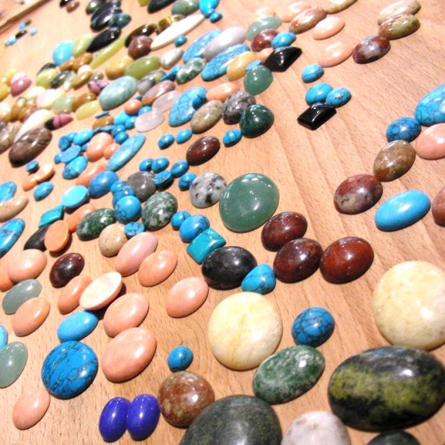 Cabochons in multiple colors laid out on the bench