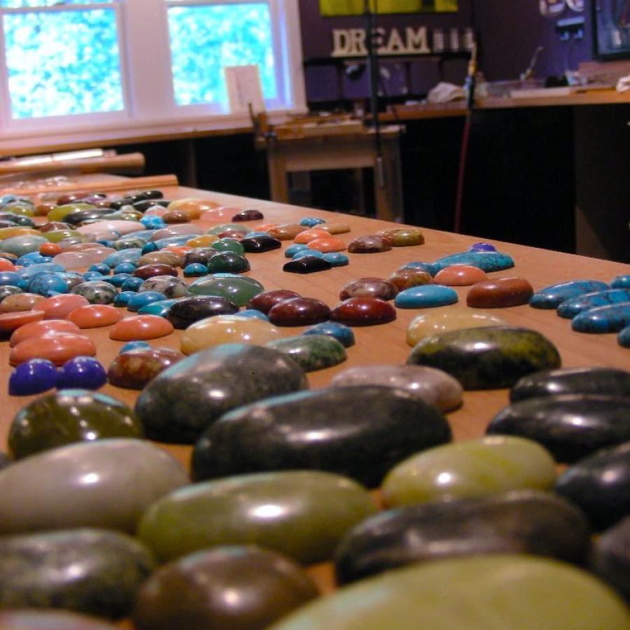 Cabochons in multiple colors laid out on the bench