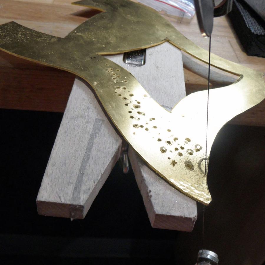 sawing and piercing the brass piece on bench pin