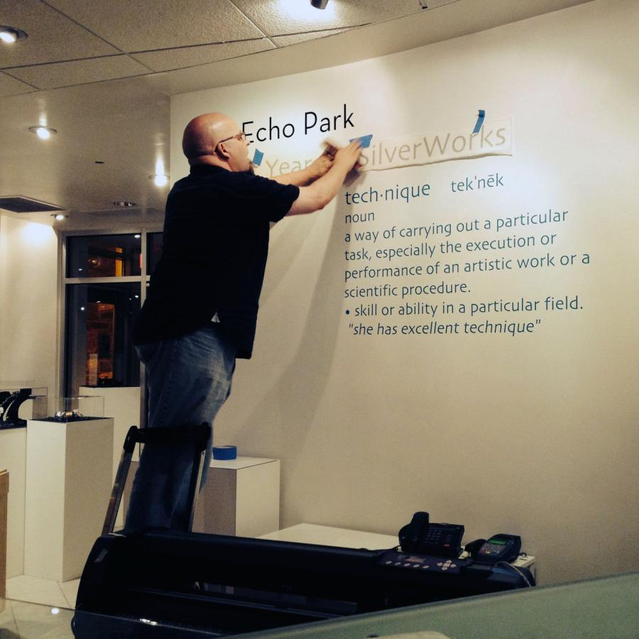 Bryan on step stool putting up vinyl text