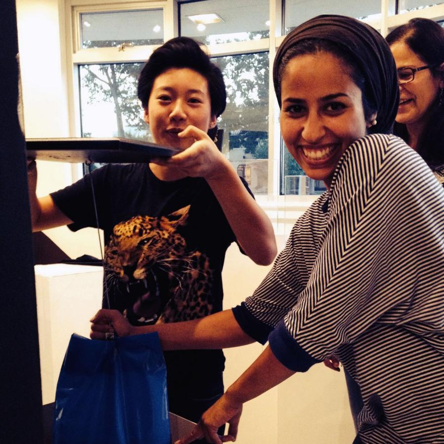 Kelly, Ilsa and Mawadda smiling at camera while assembling display stands