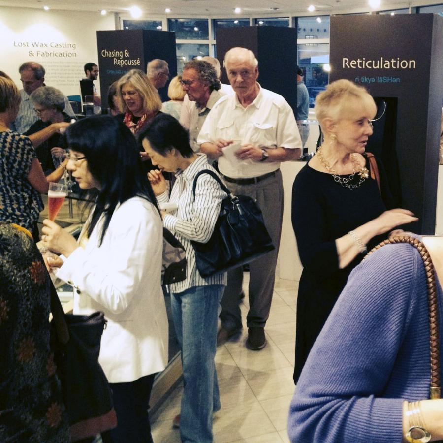 People gathered in gallery with refreshments and looking at the work