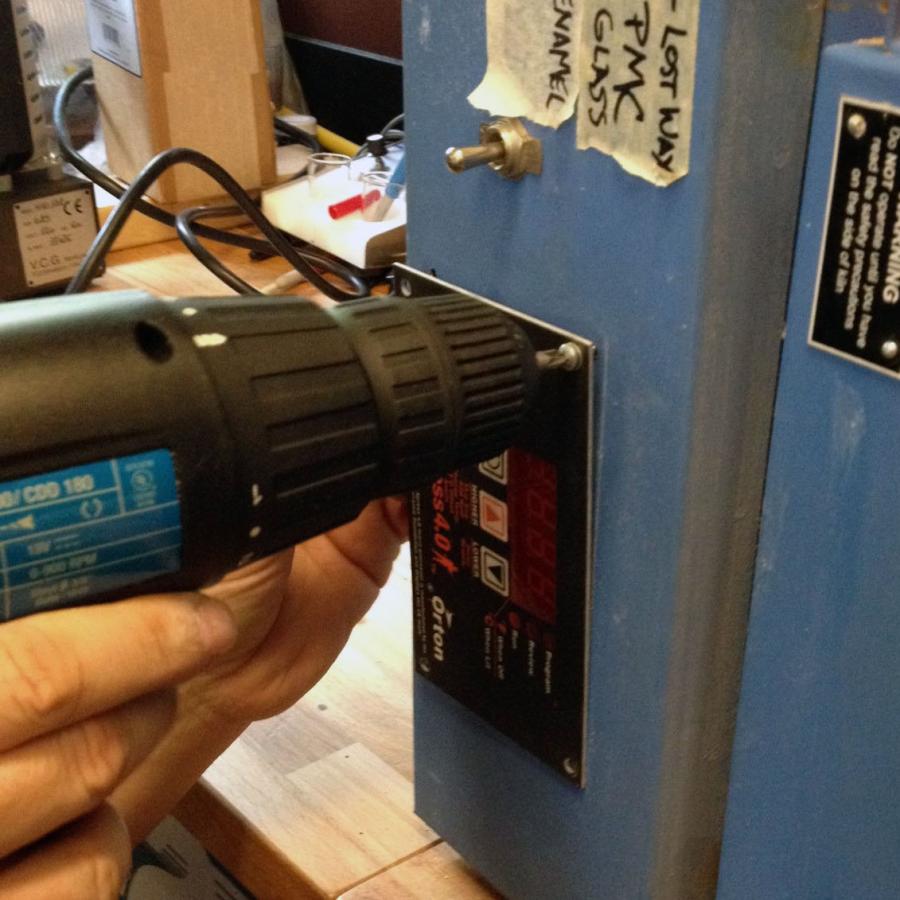 using a power drill to open the kiln 