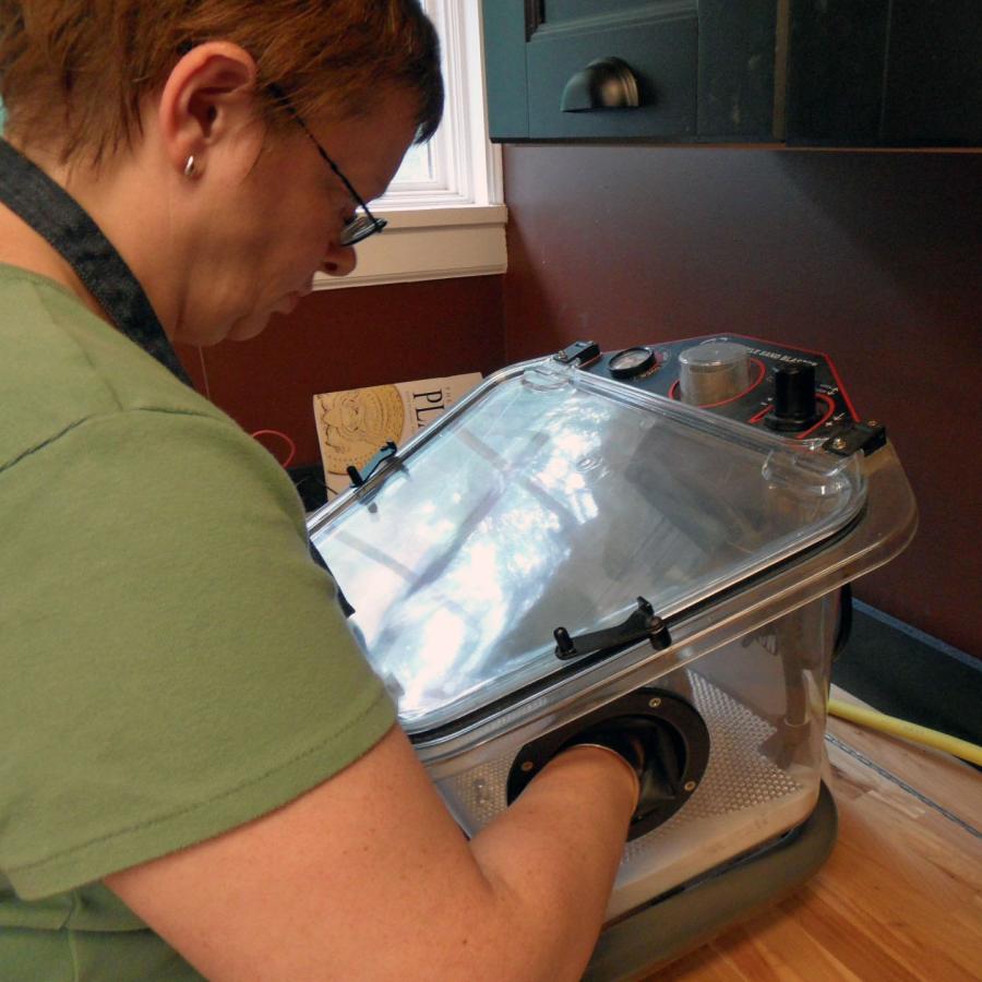 Kristin with her hands inside the sand blaster