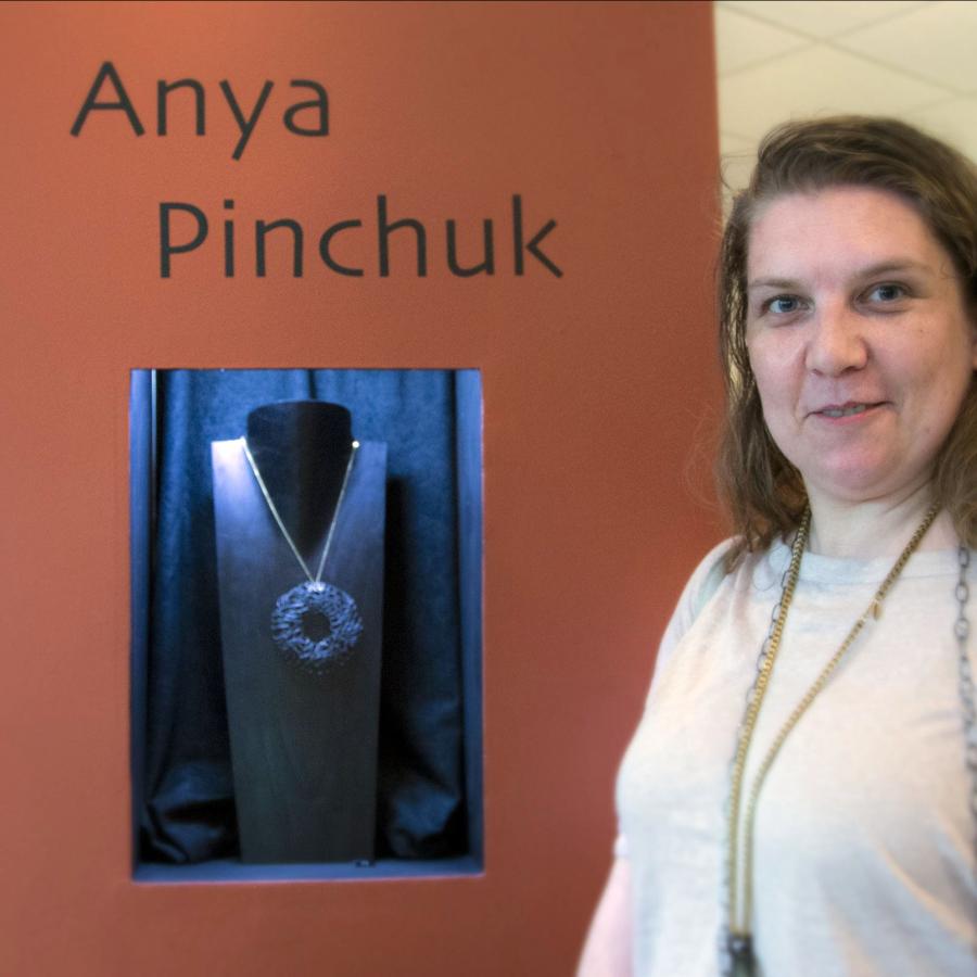 Anya standing by a tower display with her name and work