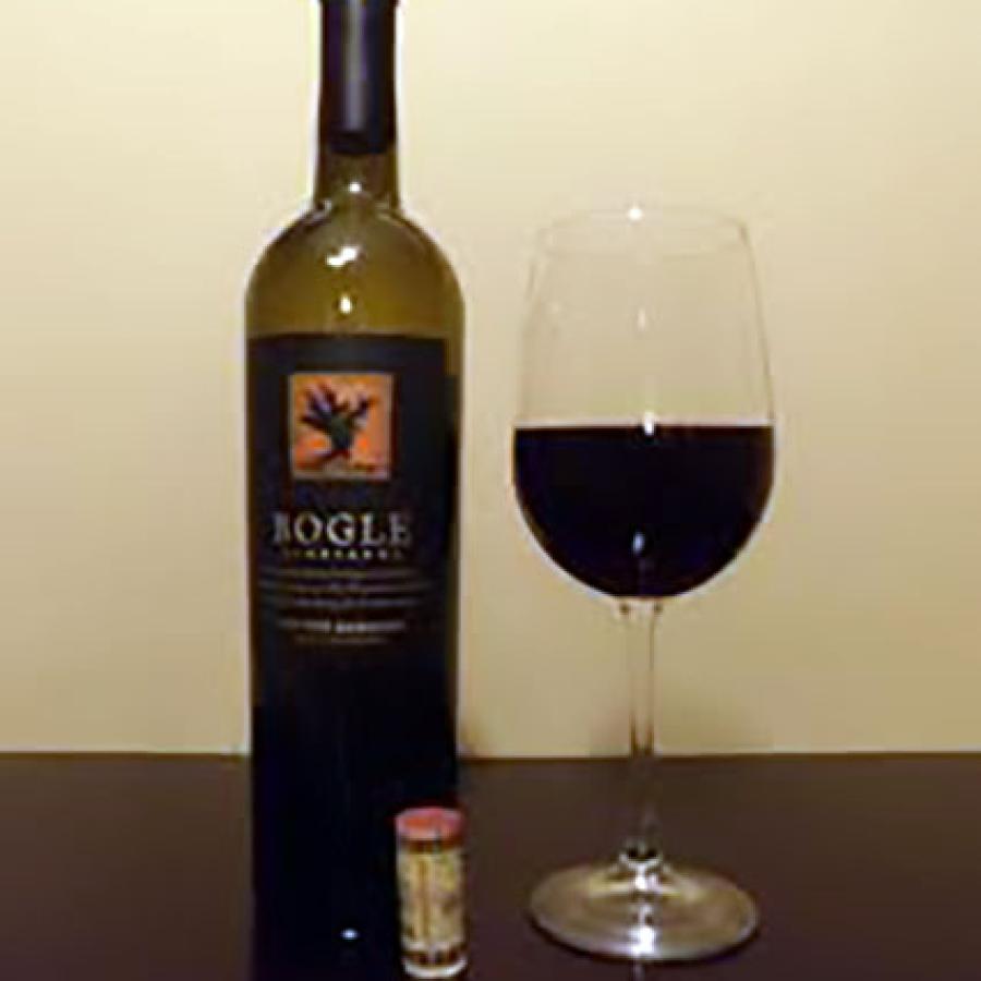 Bottle of red wine, uncorked next to filled wine glass