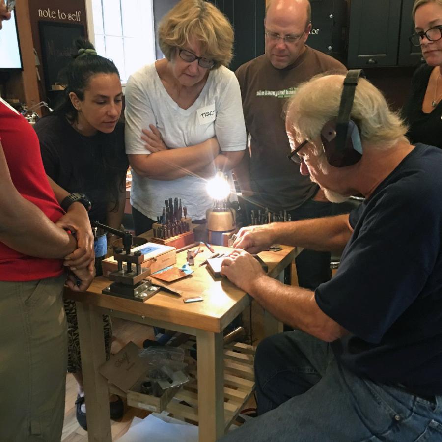 alan showing stamping with students gathered around bench