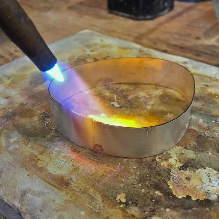 using torch to solder the silver sheet strip to create bangle