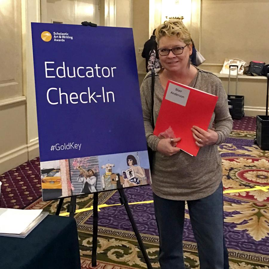 Blair standing next to educator event sign