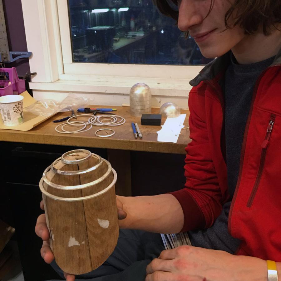 Louis holding wooden jig to form wire cage