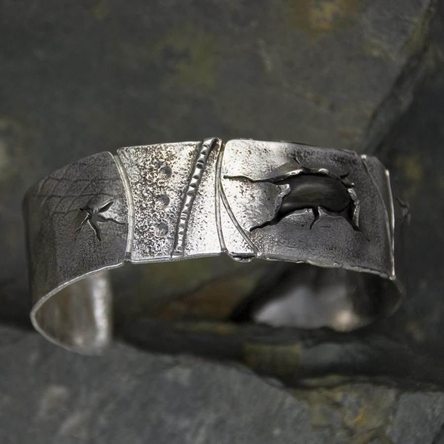 Silver bracelet with a black stone on slate.