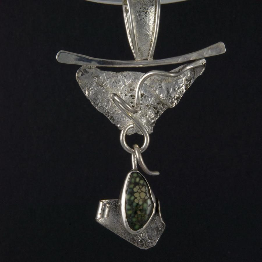 Silver pendant necklace with dinosaur bone stone, close-up photograph.