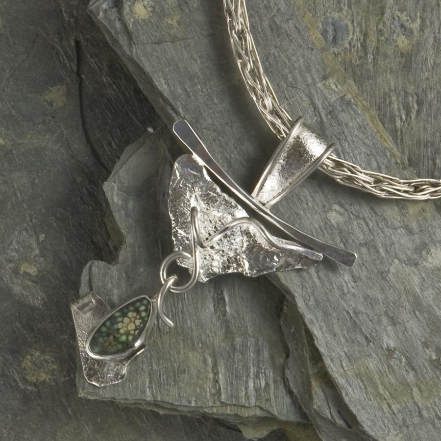 Silver and dinosaur bone pendant on slate background