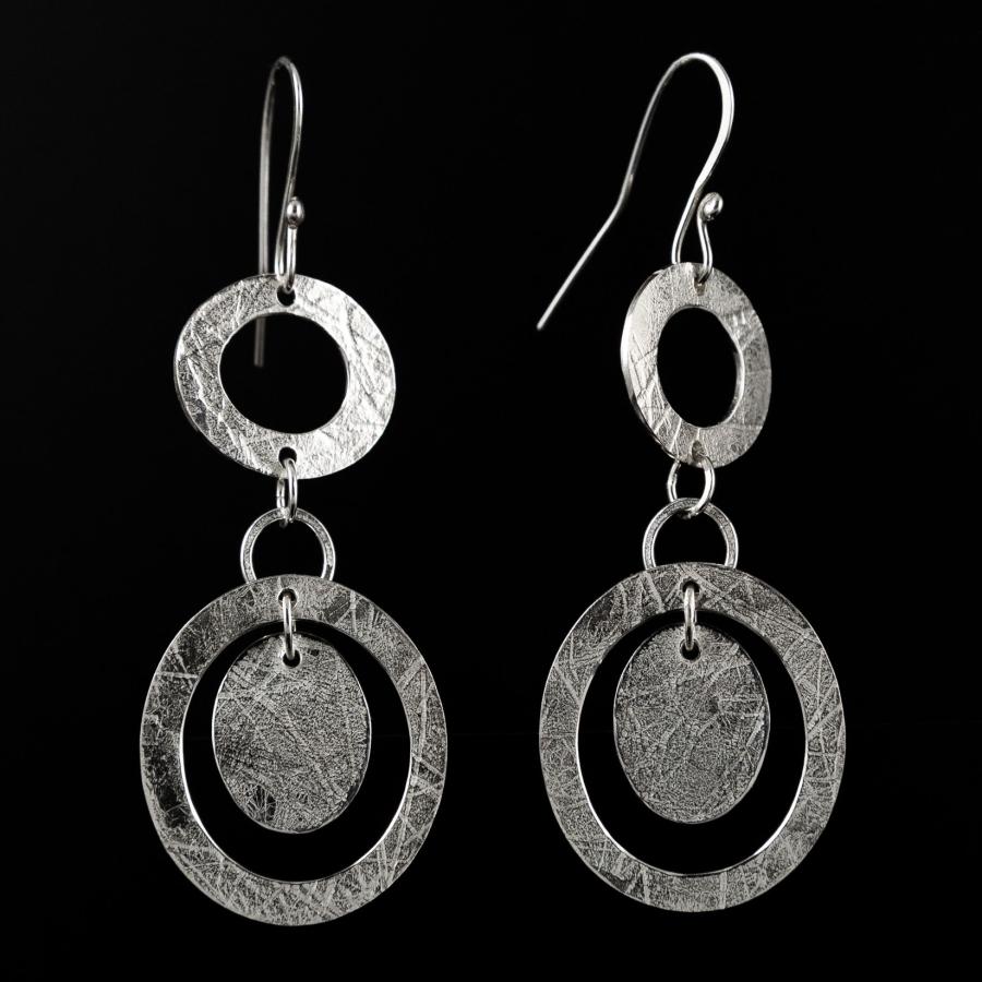 Silver dangle earrings on a black background.