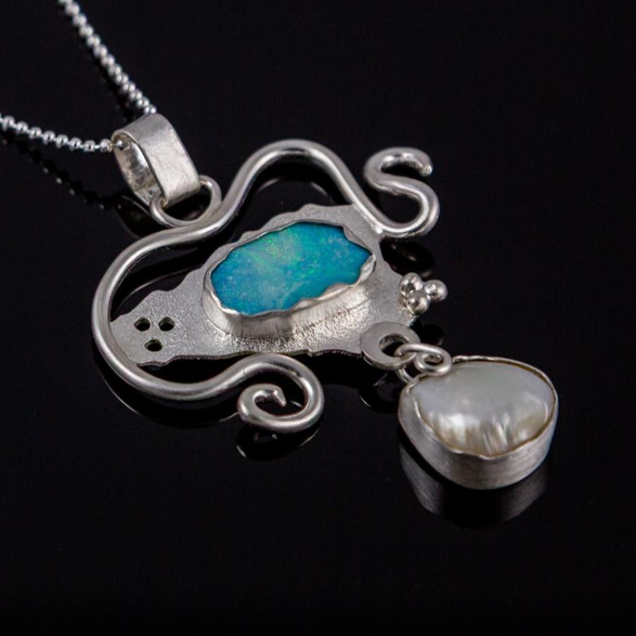 Silver necklace with blue and white stones on black background.