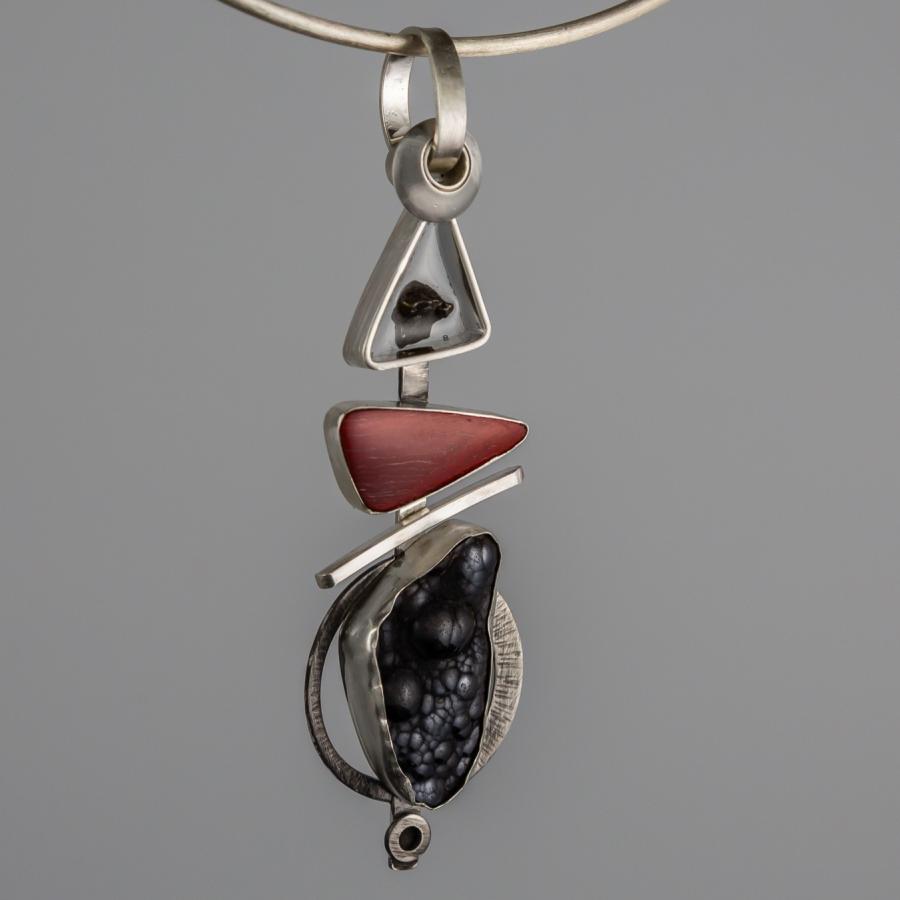 Silver pendant necklace with red and black stones.