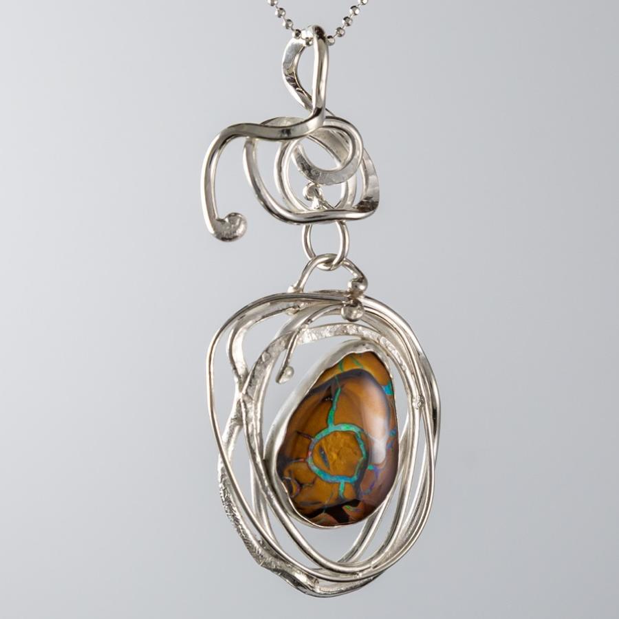 Silver necklace with intricate pendant and oval bolder opal.