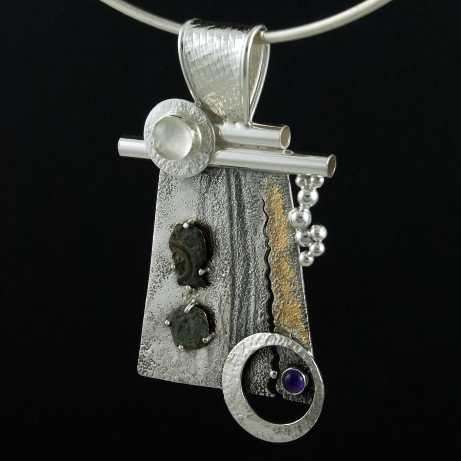 Silver pendant necklace against black background.