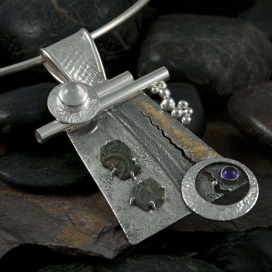 Silver necklace on dark pebbles, product photography.