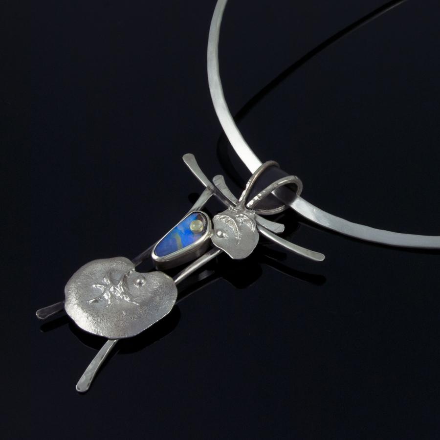 Silver necklace with blue stone on black background.