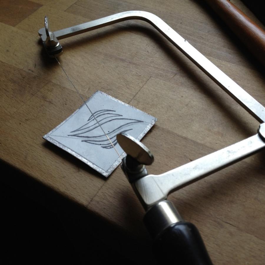 Jeweler's saw next to sketched design.